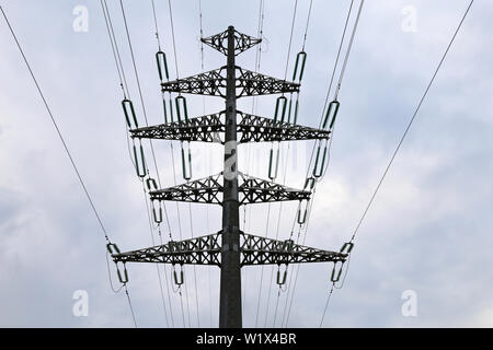 High voltage power line supports with electrical wires on cloudy sky. Electricity transmission lines, power supply concept Stock Photo