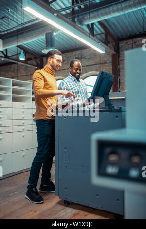 Discussing new project. Two colleagues working in publishing office discussing new project together Stock Photo