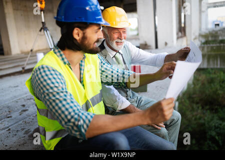 Engineer, foreman and worker discussing in building construction site Stock Photo