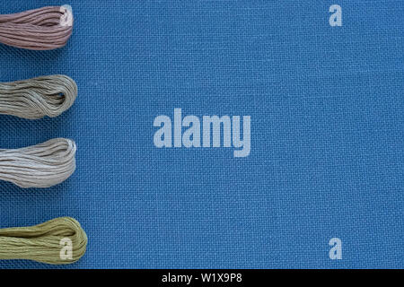 Multi-colored threads for embroidery on blue canvas. Place for text Stock Photo