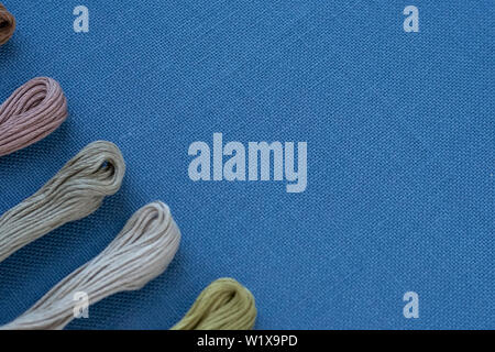 Multi-colored threads for embroidery on blue canvas. Place for text Stock Photo