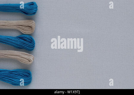 Multi-colored threads for embroidery on blue canvas. Place for text. Stock Photo