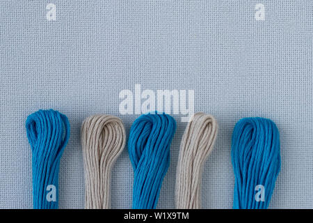 Multi-colored threads for embroidery on blue canvas. Place for text. Stock Photo