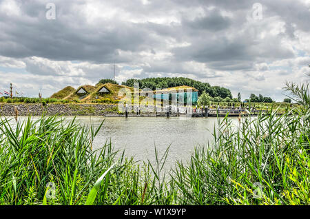 Werkendam, The Netherlands, July 3, 2019: view between reeds across the water towards the soil-covered Biesbosch museum, restaurant and jetty Stock Photo