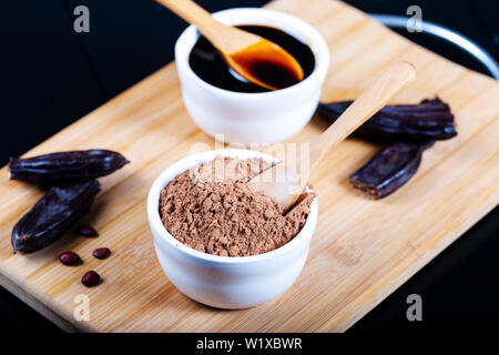 Carob pods and carob powder over wooden background Stock Photo