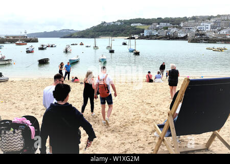 St. Ives, Cornwall, UK. June 24, 2019. Holidaymakers enjoying the sands overlooking the Harbor with high tide at St. Ives in Cornwall, UK. Stock Photo