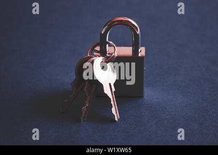 Silver metal check lock and three keys on dark blue background. Modern padlock concept. Stock Photo