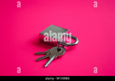 Silver metal check lock and three keys on neon pink background. Modern padlock concept. Stock Photo