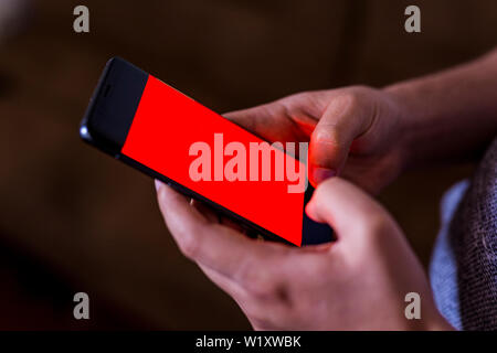 man hand holding mobile phone in coffee shop. Man using smartphone. Empty screen with copy space for text or content Stock Photo