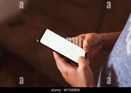 man hand holding mobile phone in coffee shop. Man using smartphone. Empty screen with copy space for text or content Stock Photo