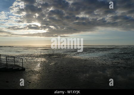 Early sunset on the North Sea directly on the beach. Orange/Blue sky and low tide. Stock Photo