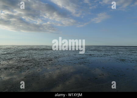 Early sunset on the North Sea directly on the beach. Orange/Blue sky and low tide. Stock Photo