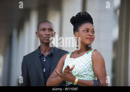 Young business people standing watch look both in the same direction. Stock Photo