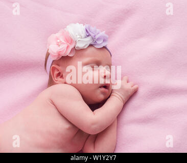 newborn baby girl sleeping with flowers on her head Stock Photo