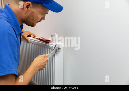 house heating system installation plumber installing radiator Stock Photo