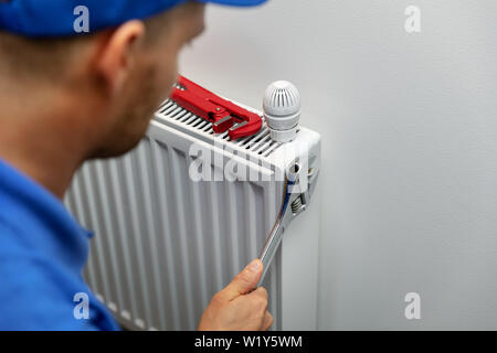 heating system installation and maintenance service. plumber installing radiator Stock Photo