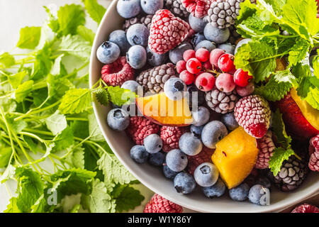 Frozen fruits blueberries blackberry raspberry red currant peach and herbs melissa Stock Photo