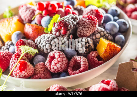 Frozen fruits blueberries blackberry raspberry red currant peach and herbs melissa Stock Photo