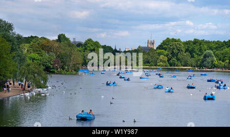 paddle boats on the Serpentine in London's Hyde Park, with the Houses of Parliament in the background Stock Photo