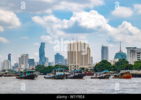 BANGKOK, THAILAND, OCT 23 2017, Group of a tugs in one line pull a heavy cargo upstream of the Chao Phraya River in Bangkok. Stock Photo