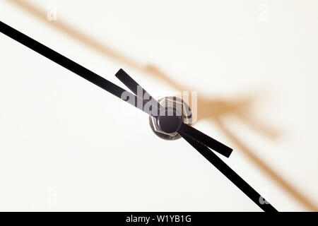 Closeup view of a simple wall watch, details of minute and hour hands on white background.
