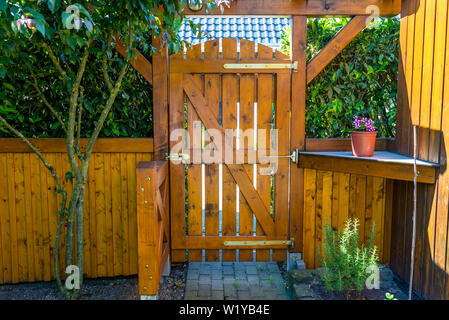 Wooden gate and fence on the back of the home garden. The gate is closed with a padlock. Stock Photo