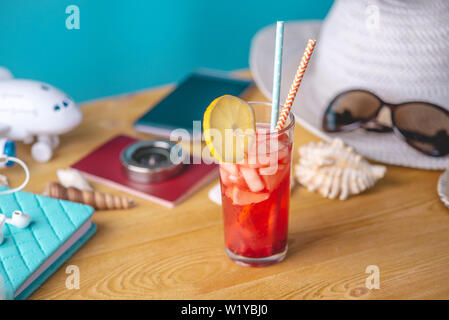 Glass of red lemonade drink with lemon and fruit and straw on the table. Concept of summer Sunny vacation at the resort. Stock Photo