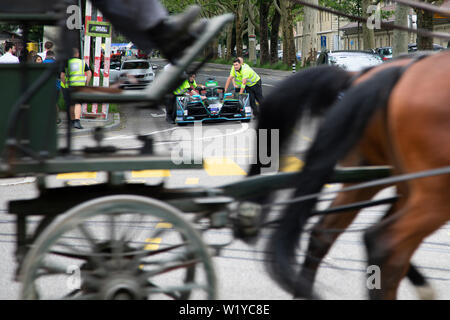 A horse caddy speeds past while crew members push one of the HWA Formula E cars from the pitlane back to the garage ahead of the  ABB FIA Formula E race in Bern. Stock Photo