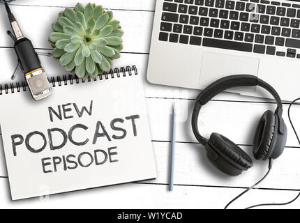 top view of text NEW PODCAST EPISODE on notepad with laptop computer, potted plant and recording microphone on white wooden table, podcasting concept Stock Photo