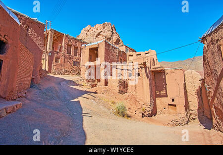 The fork in medieval hilly road with a view on old shabby adobe buildings of famous red village, Abyaneh, Iran. Stock Photo