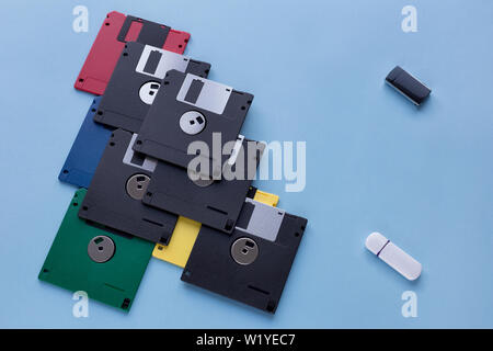 The evolution of digital data storage device. Floppy disks vs small flash drives. Isolated on a blue background. Modern and retro technology. Stock Photo