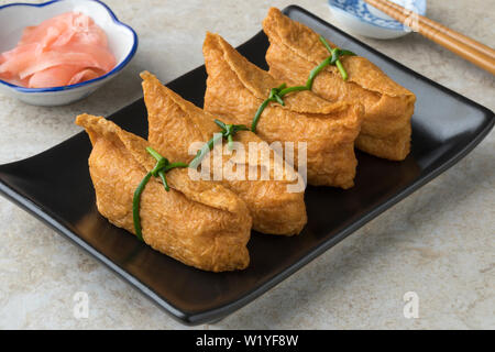 Traditional Japanese fried marinated tofu stuffed with rice, called inari age Stock Photo