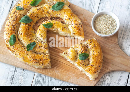 Phyllo pie stuffed with feta decorated with mint leaves: top view Stock Photo