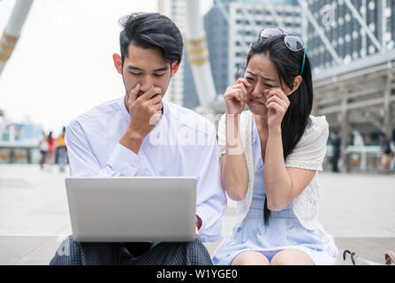 Couples are sit using laptop with sad about incident something in city Stock Photo