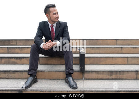 Young businessman jobless sitting on stair in the city. Isolated on white background Stock Photo
