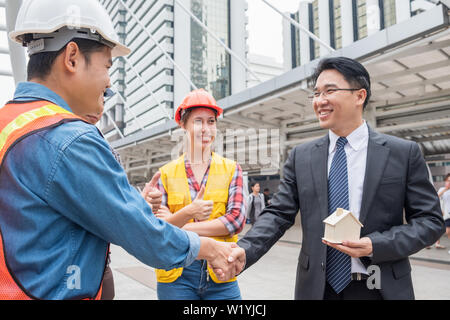 Engineer group handshake agreement with businessman for residential construction project Stock Photo