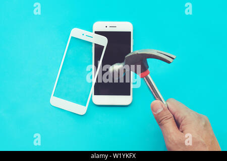 Male hand with hammer on tempered glass shield or film screen cover.Mobile phone protector concepts ideas Stock Photo