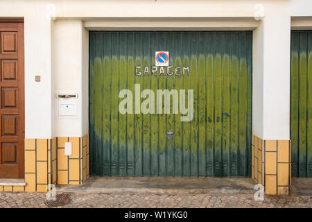 Green painted garage door in house in Alvor, Algarve, Portugal Stock Photo