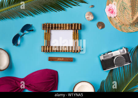 Photo frame, hat, camera, sunglasses, coconuts, on the blue background. Beach theme on the blue background. Top view. Stock Photo