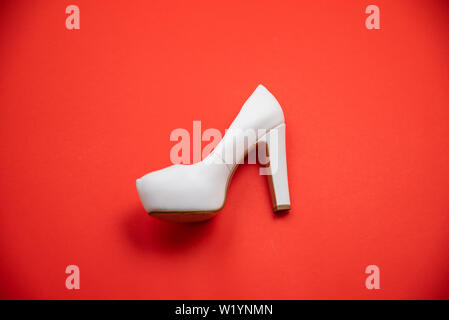 White high heeled shoes on red background - top view concept - blank empty room space for text or copy. Suitable for holidays like Valentine's or Chri Stock Photo