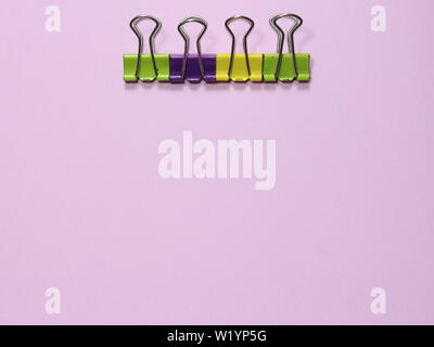 Colorful paper clip on pink millennial background with copy space to insert the text. Office stuff. Minimalism. Metaphor to teamwork and hierarchy Stock Photo