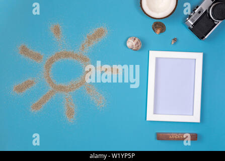 Photo frame and camera on blue background. Sun drawn by the sand on blue background. Top view. Stock Photo