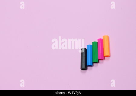 Five colorful pen cap on a pink millennial background with copy space to insert the text. Office stuff. Minimalism. Metaphor to teamwork and hierarchy Stock Photo