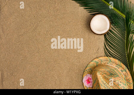 Beach theme on the sand background. Palm leaves, coconut, hat on the sand. Top view. Stock Photo
