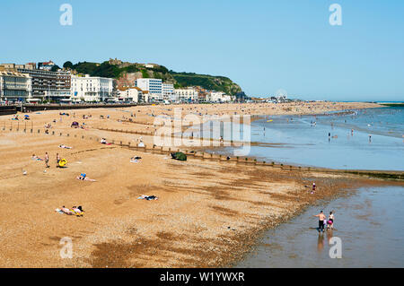 Hastings beach, East Sussex, UK, in June, with crowds on the beach and in the sea Stock Photo