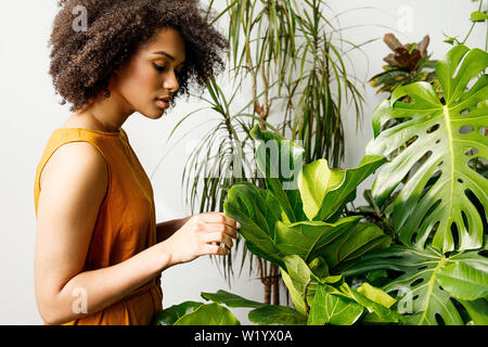 Side view of woman florist standing in her botanical garden and working Stock Photo