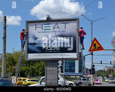 Varna, Bulgaria, July 2018. Two workers set an advertising poster for electronic  cigarettes Iqos on a billboard near the road Stock Photo - Alamy