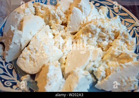 Sliced home-made sheep's cheese on a decorative blue plate with a beautiful pattern on the festive table Stock Photo