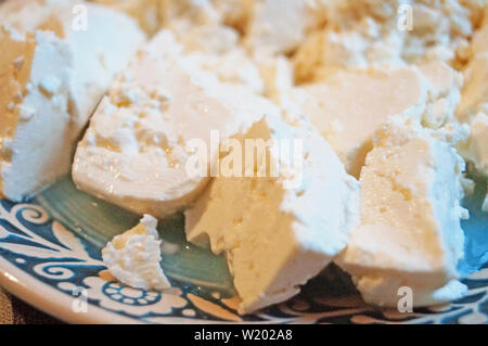 Sliced home-made sheep's cheese on a decorative blue plate with a beautiful pattern on the festive table Stock Photo
