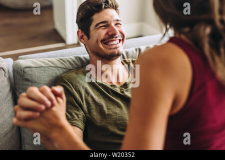 Cheerful young man sitting with her girlfriend at home. Couple enjoying free time at home. Stock Photo